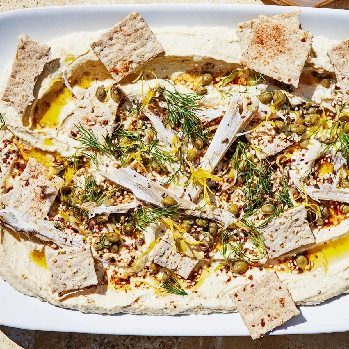 Driftwood Beach appetizer showcases flaked smoked fish on creamy hummus, served with crisp crackers.