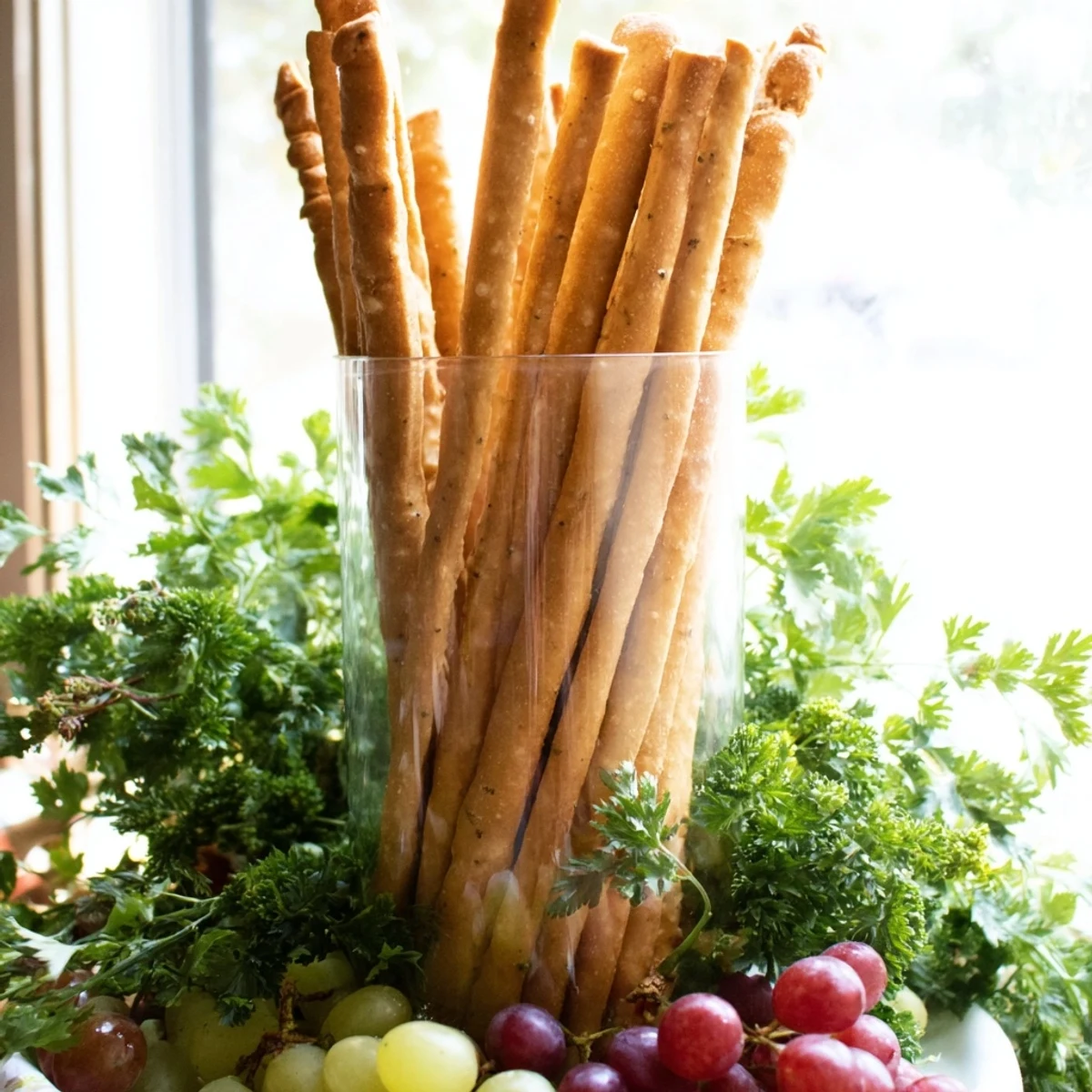 The Vertical Forest appetizer: tall breadsticks in jars with vibrant parsley and juicy grape clusters.