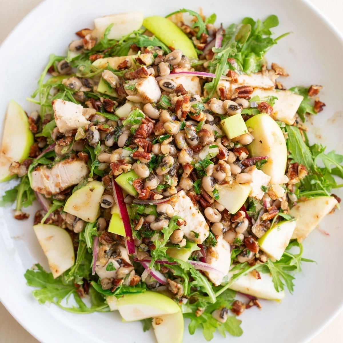 A bowl of Chicken and Apple New Years Luck Salad, ready to serve, with a sprinkle of toasted pecans.