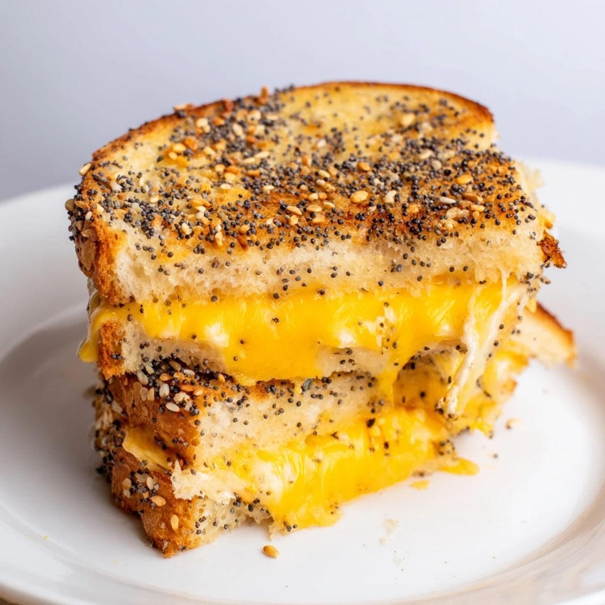 Golden-brown everything bagel grilled cheese, melty cheese oozing from toasted, crispy bread.