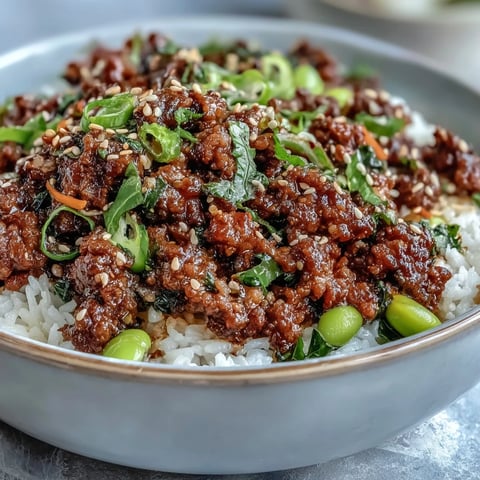 Hot Korean Ground Beef Bowl with gochujang glaze, served over white rice with fresh veggies and kimchi.
