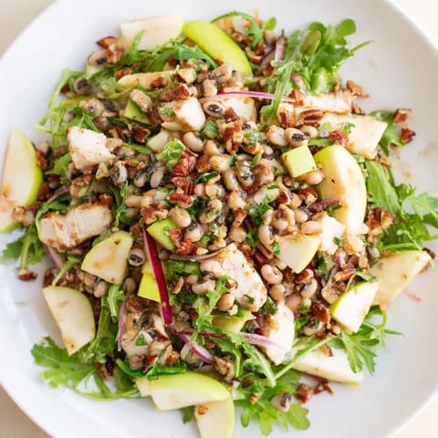 A bowl of Chicken and Apple New Years Luck Salad, ready to serve, with a sprinkle of toasted pecans.