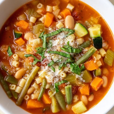 A close-up of a rustic Tomato Basil Minestrone, thick with vegetables and served in a bowl.