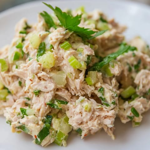 Overhead shot of freshly prepared Spicy Zesty Tuna Salad served in crisp lettuce cups, garnished with fresh lemon wedges on a rustic wooden table.