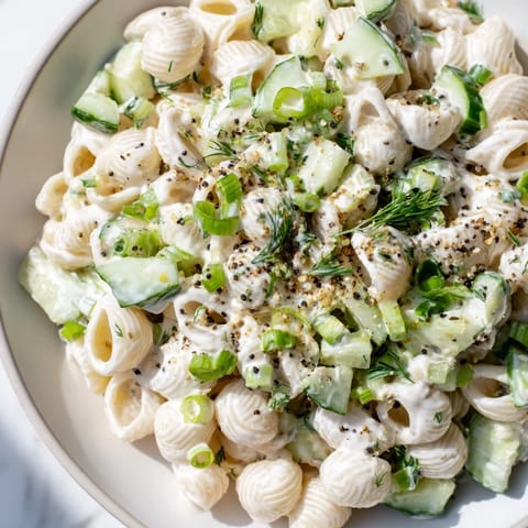 Chilled Cucumber Crunch Pasta Salad featuring tender shells, vibrant green onions, and a tangy sour cream sauce ready for summer picnics.  