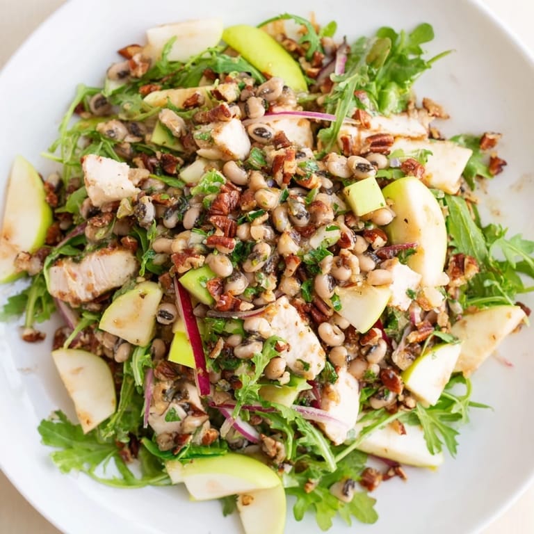 A bowl of Chicken and Apple New Years Luck Salad, ready to serve, with a sprinkle of toasted pecans.
