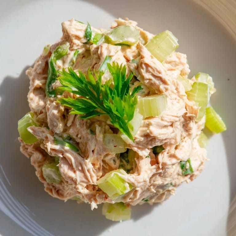 Spicy Zesty Tuna Salad piled high on toasted whole grain bread, showcasing the vibrant red sriracha streaks and crunchy celery textures.