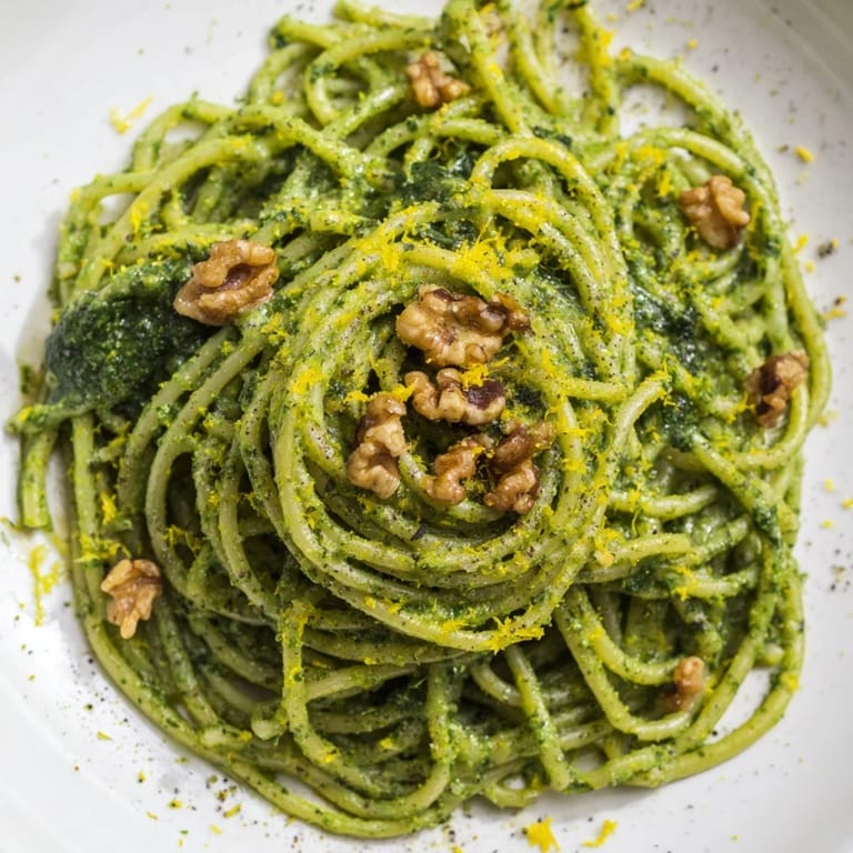 Steaming bowls of creamy spinach walnut pasta are ready to serve, garnished with extra chopped walnuts for crunch.