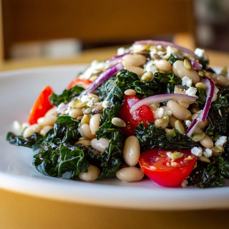 Freshly prepared White Bean and Kale Salad with bright cherry tomatoes, thinly sliced red onion, and a drizzle of zesty lemon-garlic dressing ready to serve.