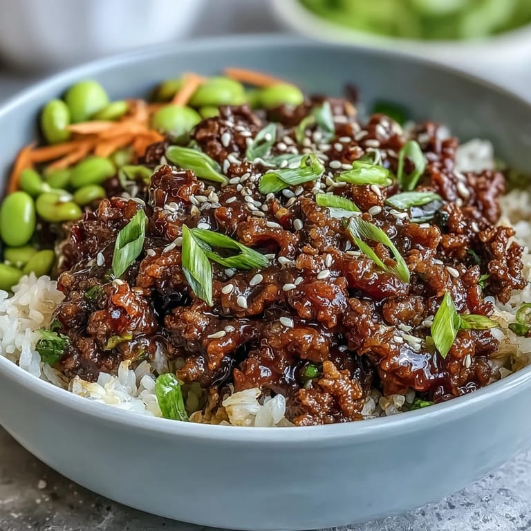 A prepared Korean Ground Beef Bowl featuring edamame, cucumber, and carrots, garnished with green onions and sesame seeds.