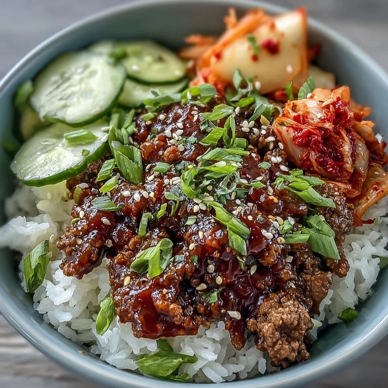 An easy Korean Beef Bowl dinner idea with spicy gochujang beef, steamed rice, fresh cucumber slices, and chopped kimchi, arranged neatly in a ceramic bowl.