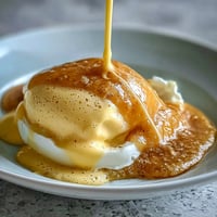 Silky, golden blender hollandaise sauce drizzled over poached eggs and asparagus, ready for a luxurious brunch.