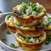 Golden brown Spring Frittata Muffins studded with vibrant green vegetables.